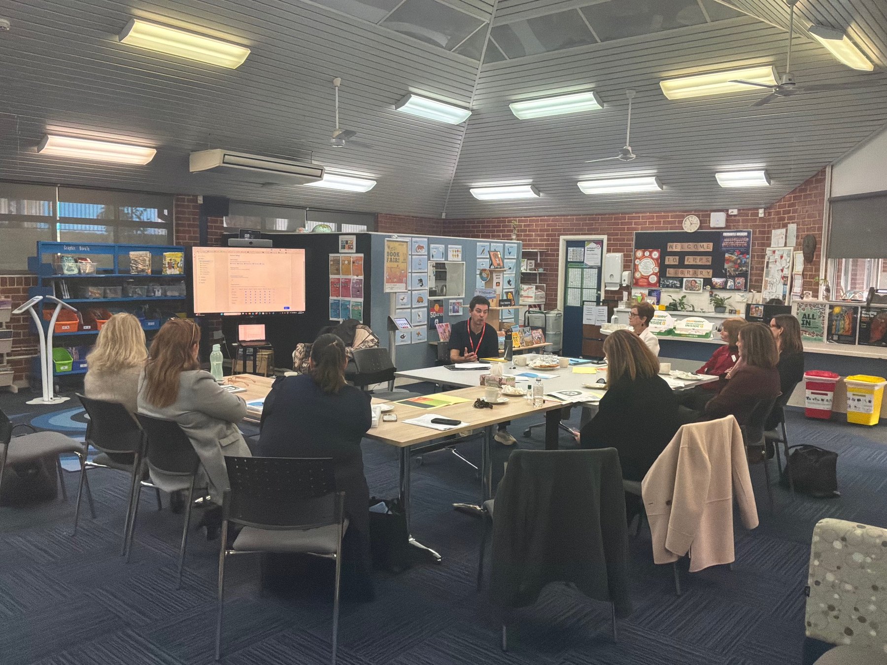 Arpad Pinto presenting Dotti to a forum of primary school principals seated around a table in the school library at Floreat Park Primary School